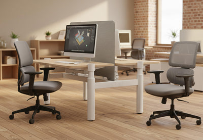 Støtte Flex Desk Chair displayed in a modern office interior, featuring two chairs positioned behind a desk, with exposed brick and beige walls, wooden flooring, large windows and high ceilings, highlighting ergonomic task seating for contemporary workspaces.