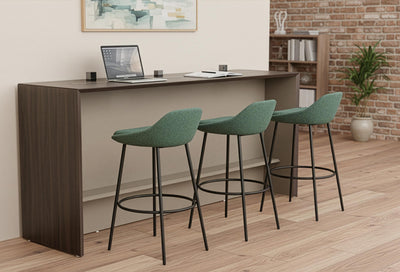 Børge Collaboration Office Stools arranged at a breakfast bar in a modern office breakout space, featuring three contemporary stools set against beige and exposed brick walls with wooden flooring and greenery. This image showcases the collaborative bar-height seating for flexible workplace environments. 